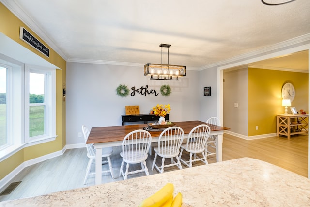 dining space featuring a chandelier, light hardwood / wood-style floors, and crown molding