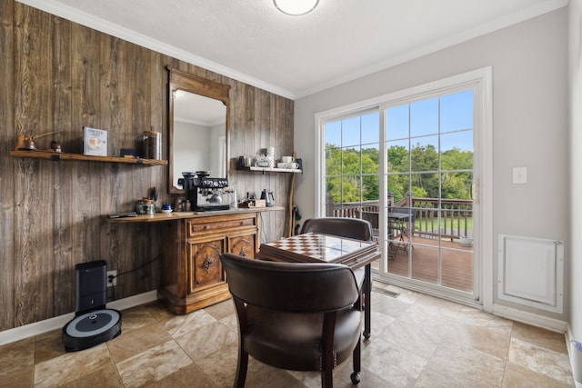 dining space featuring ornamental molding, wooden walls, and a textured ceiling