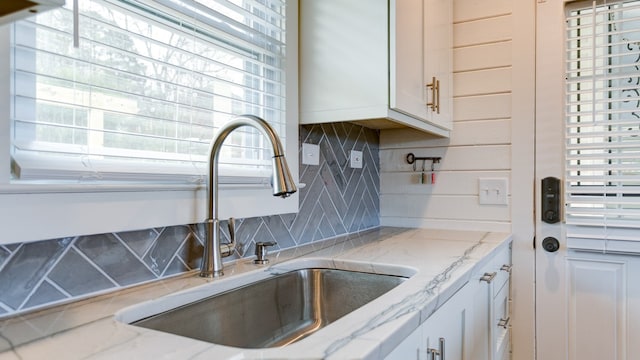 kitchen featuring a healthy amount of sunlight, light stone counters, and sink