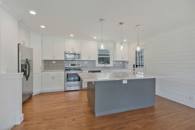 kitchen with white cabinetry, appliances with stainless steel finishes, decorative light fixtures, and light wood-type flooring