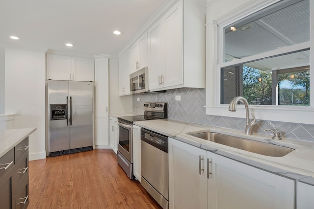 kitchen with light hardwood / wood-style flooring, sink, light stone countertops, white cabinetry, and appliances with stainless steel finishes