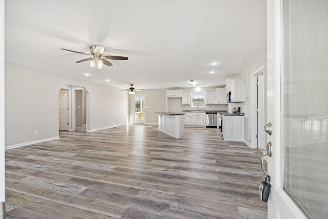 unfurnished living room featuring ceiling fan, sink, and light wood-type flooring