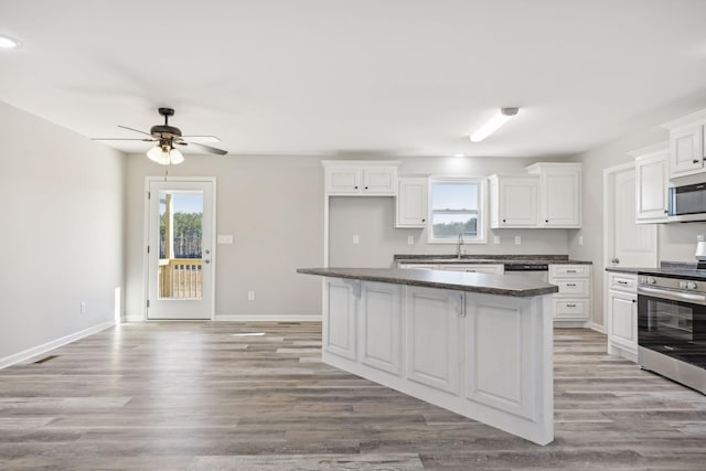 kitchen with stainless steel appliances, ceiling fan, light hardwood / wood-style flooring, white cabinets, and a center island