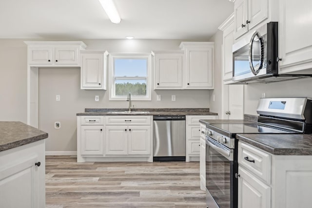 kitchen featuring white cabinetry, sink, stainless steel appliances, and light hardwood / wood-style floors