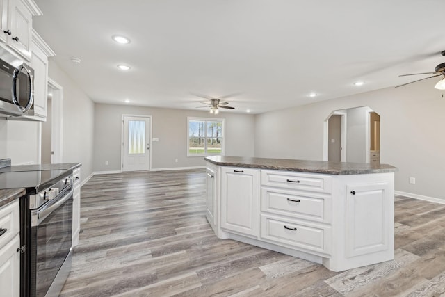 kitchen featuring ceiling fan, a kitchen island, appliances with stainless steel finishes, light hardwood / wood-style floors, and white cabinetry