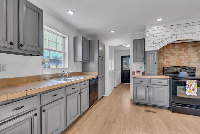 kitchen with black appliances, crown molding, sink, tile counters, and light hardwood / wood-style floors