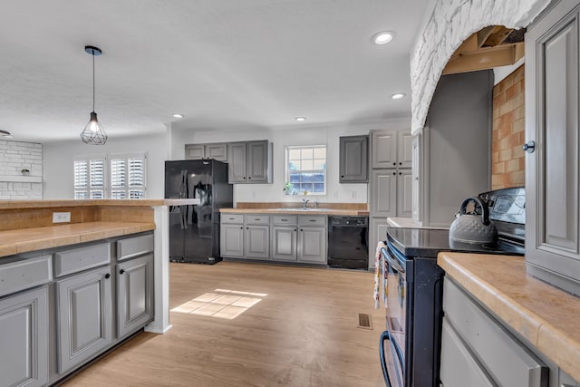 kitchen with light hardwood / wood-style floors, black appliances, gray cabinetry, backsplash, and decorative light fixtures