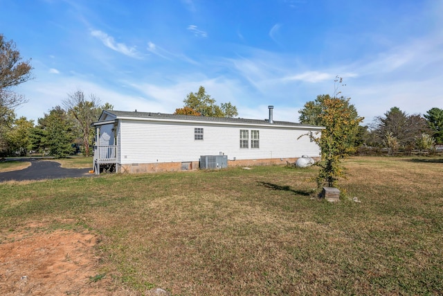 back of property featuring central AC unit and a yard