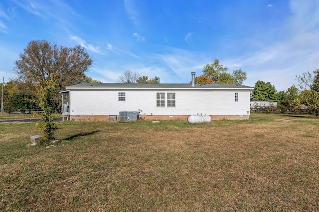 rear view of property featuring cooling unit and a lawn