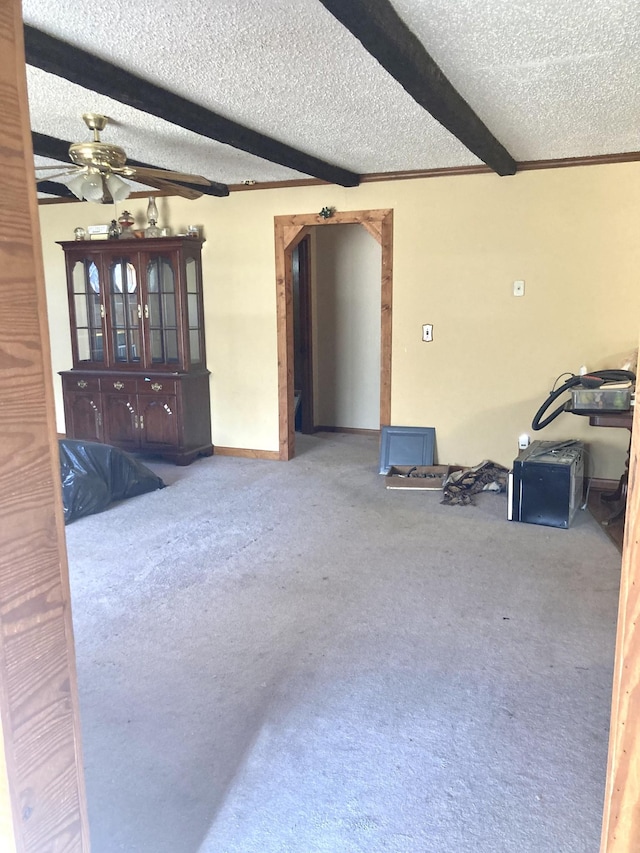 spare room featuring baseboards, ceiling fan, a textured ceiling, carpet floors, and beam ceiling