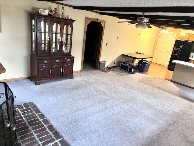 living room with a textured ceiling, light carpet, a ceiling fan, baseboards, and beamed ceiling