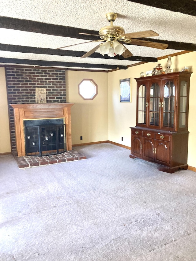 unfurnished living room with baseboards, a fireplace with raised hearth, a textured ceiling, carpet flooring, and beam ceiling