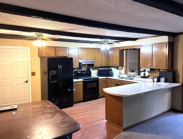 kitchen featuring a textured ceiling, a peninsula, light countertops, brown cabinets, and black appliances