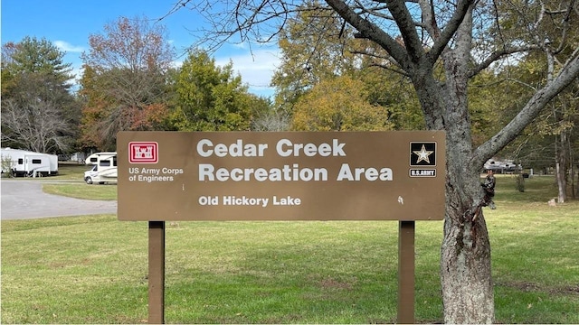 community sign with uncovered parking and a yard