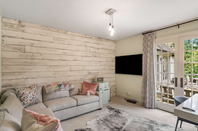 carpeted living room featuring wood walls and french doors