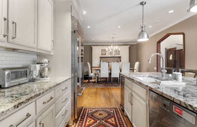 kitchen with light wood-type flooring, sink, a chandelier, and white cabinets