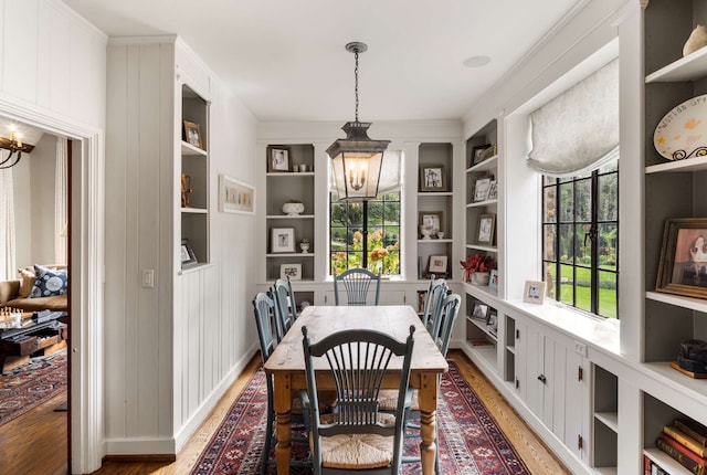 dining room featuring light hardwood / wood-style floors, built in features, a chandelier, and a healthy amount of sunlight