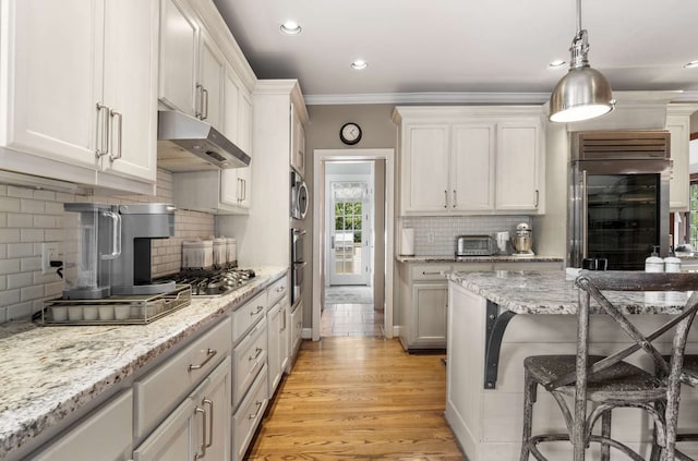 kitchen featuring white cabinetry, a breakfast bar area, light wood-type flooring, crown molding, and built in fridge