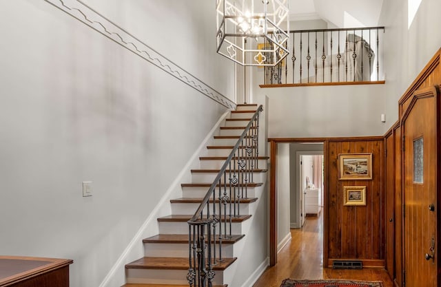 stairs featuring a notable chandelier, a towering ceiling, and hardwood / wood-style flooring