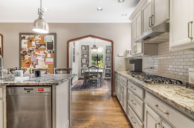 kitchen featuring hanging light fixtures, light stone countertops, stainless steel appliances, light wood-type flooring, and crown molding