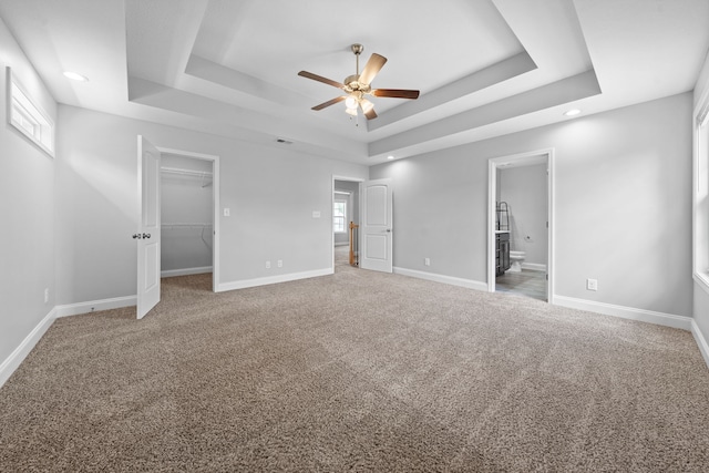 unfurnished bedroom featuring multiple windows, a tray ceiling, and ceiling fan