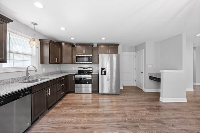 kitchen featuring wood-type flooring, decorative light fixtures, appliances with stainless steel finishes, and sink