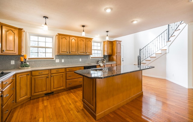 kitchen with dark wood-type flooring, pendant lighting, an island with sink, and a wealth of natural light