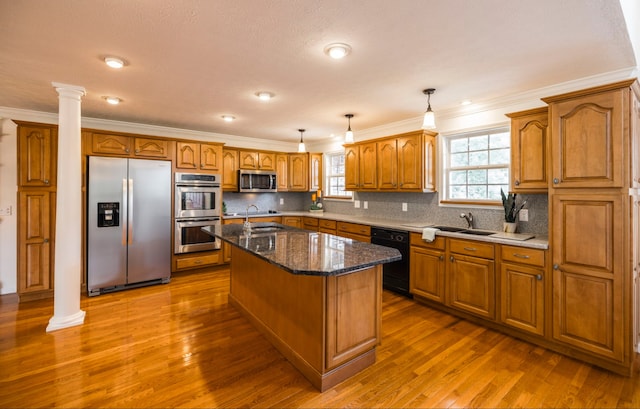 kitchen with appliances with stainless steel finishes, hanging light fixtures, dark wood-type flooring, a kitchen island, and ornate columns