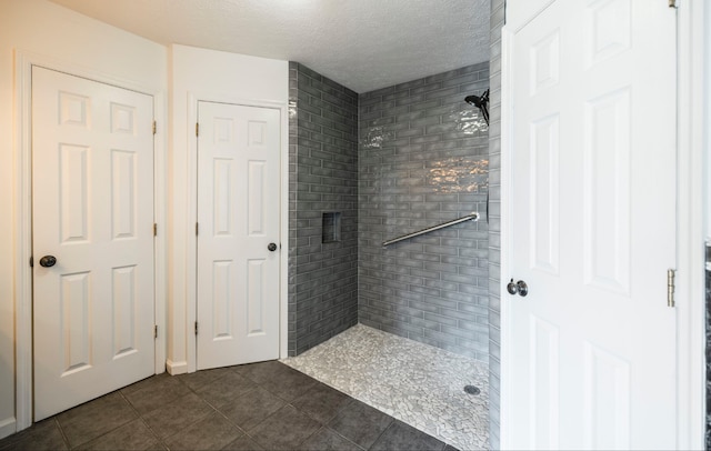 bathroom featuring a textured ceiling, tiled shower, and tile patterned floors