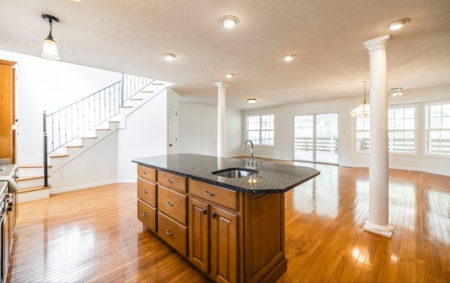 kitchen featuring sink, light hardwood / wood-style floors, plenty of natural light, and ornate columns