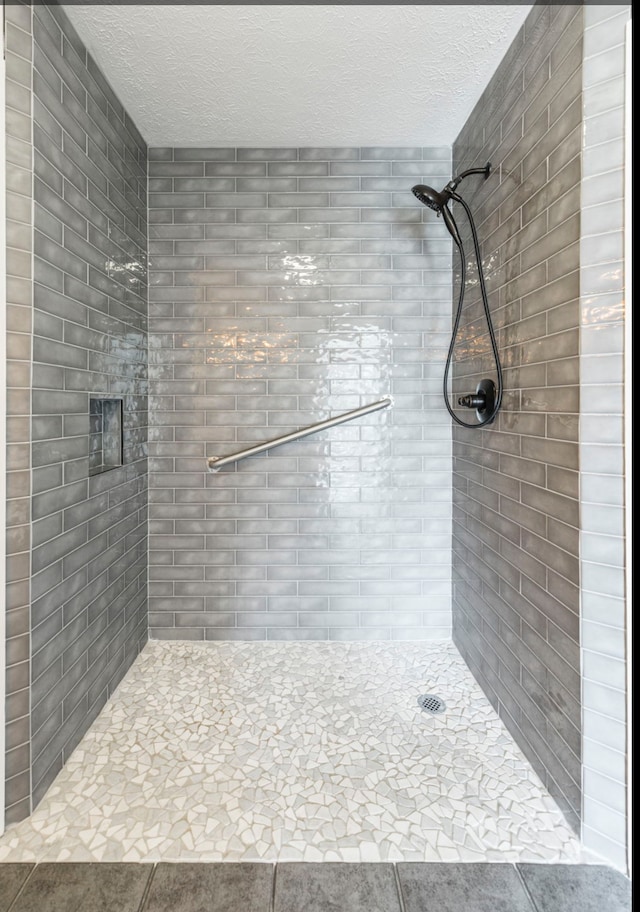 bathroom with a tile shower and a textured ceiling