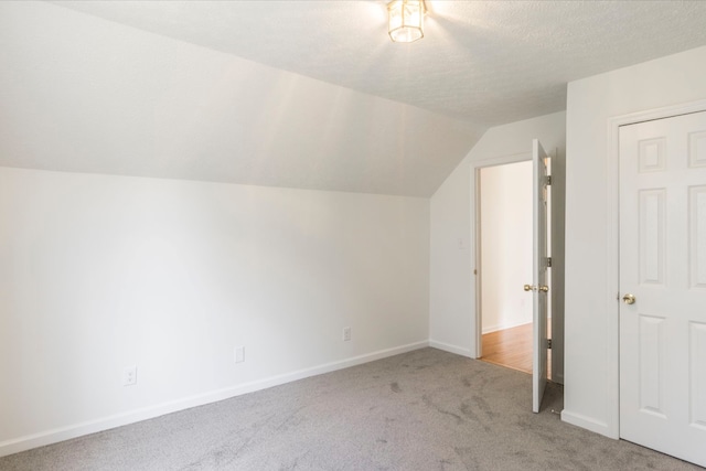 bonus room with light carpet, vaulted ceiling, and a textured ceiling