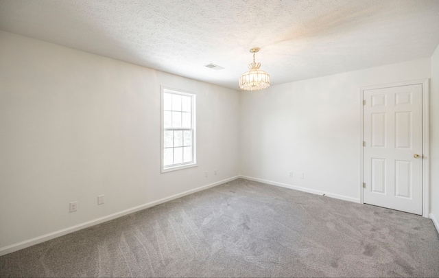 empty room with carpet floors, an inviting chandelier, and a textured ceiling