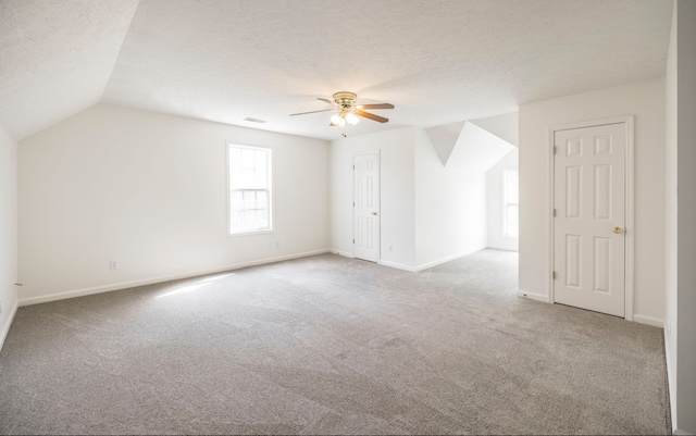 bonus room featuring ceiling fan, a textured ceiling, light carpet, and vaulted ceiling