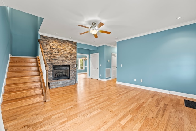 unfurnished living room with ceiling fan, a stone fireplace, ornamental molding, and light hardwood / wood-style floors