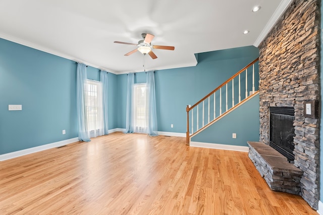 unfurnished living room featuring light hardwood / wood-style floors, crown molding, a stone fireplace, and ceiling fan