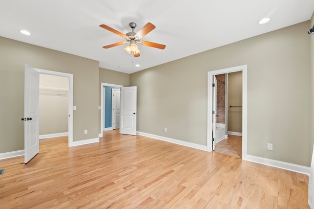 unfurnished bedroom featuring a closet, ceiling fan, a walk in closet, light hardwood / wood-style flooring, and ensuite bath