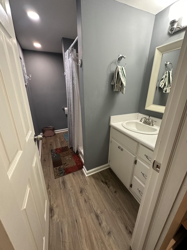 bathroom featuring baseboards, wood finished floors, a stall shower, and vanity