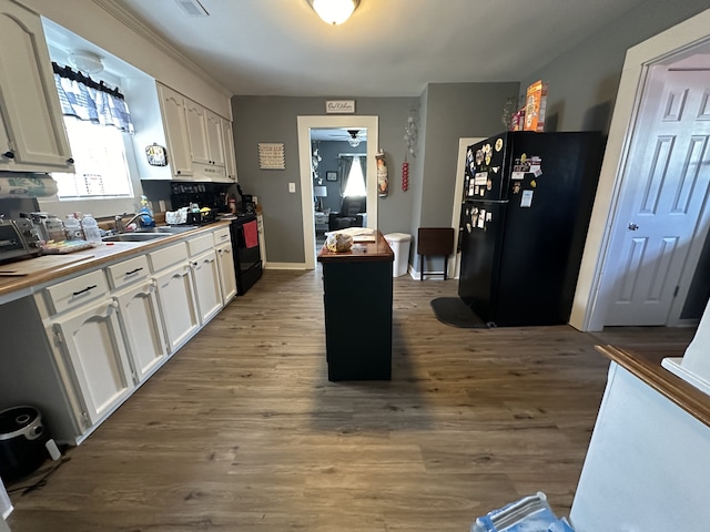 kitchen with wood-type flooring, black appliances, and white cabinetry