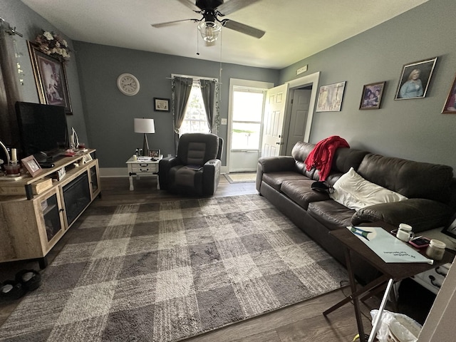 living area featuring baseboards and a ceiling fan