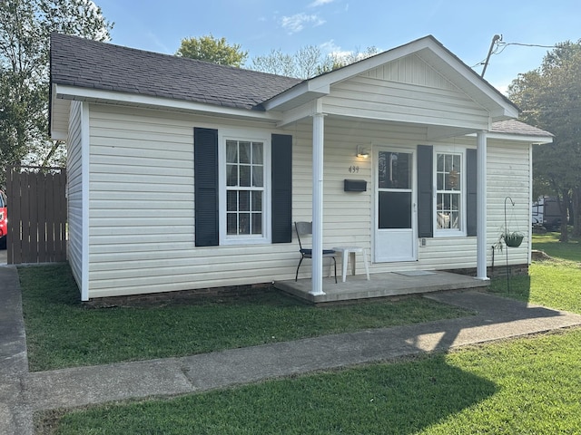 view of front of home with a front yard, fence, and roof with shingles