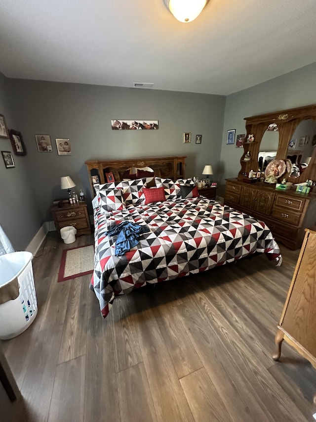 bedroom with baseboards, visible vents, and wood finished floors