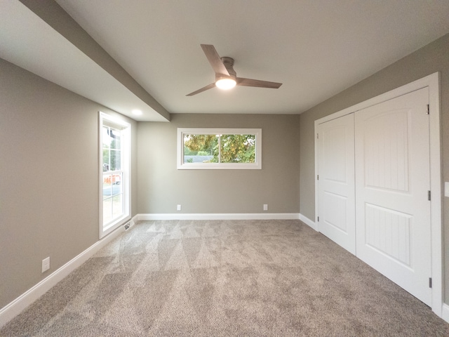 unfurnished bedroom with ceiling fan, light colored carpet, and a closet