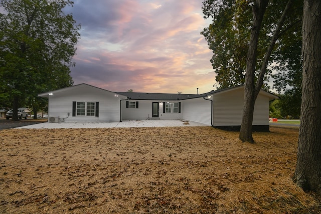 back house at dusk featuring a patio