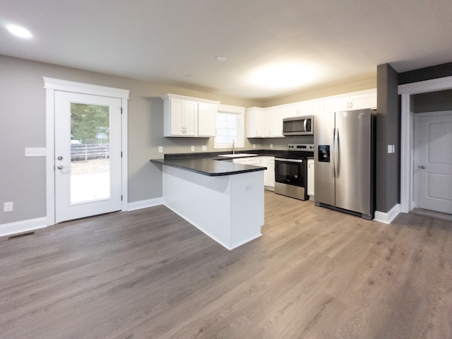 kitchen featuring stainless steel appliances, white cabinets, sink, light hardwood / wood-style floors, and kitchen peninsula