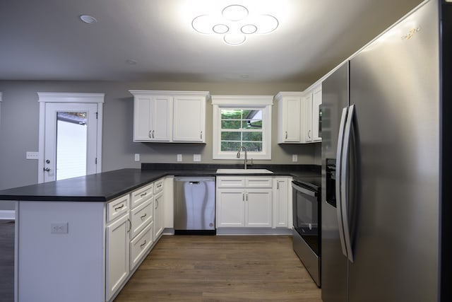 kitchen featuring stainless steel appliances, dark wood-type flooring, sink, kitchen peninsula, and white cabinetry