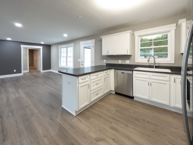 kitchen featuring sink, kitchen peninsula, white cabinetry, dishwasher, and hardwood / wood-style flooring