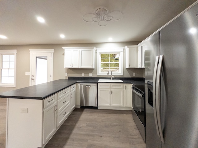 kitchen featuring kitchen peninsula, appliances with stainless steel finishes, sink, and white cabinetry