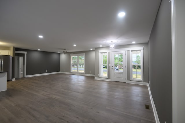 unfurnished living room with dark hardwood / wood-style flooring and ceiling fan