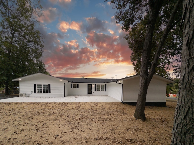 back house at dusk featuring a patio area and central AC